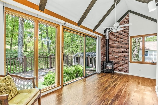 unfurnished sunroom with a wood stove, healthy amount of natural light, and wood finished floors