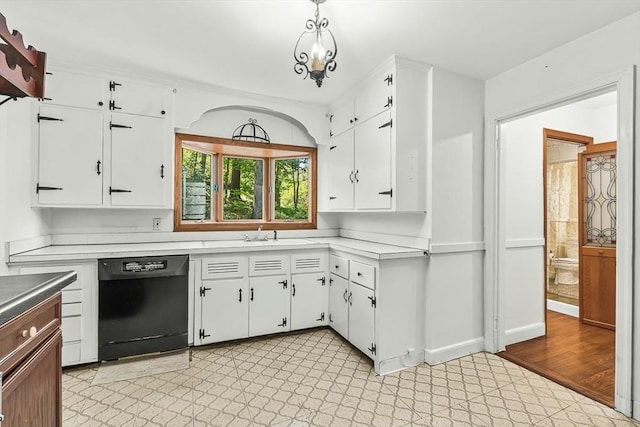 kitchen with black dishwasher, light countertops, white cabinets, a sink, and decorative light fixtures