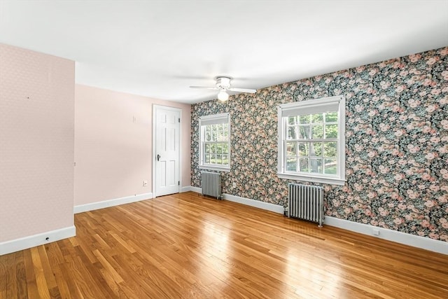 spare room with radiator, light wood-style flooring, baseboards, and wallpapered walls