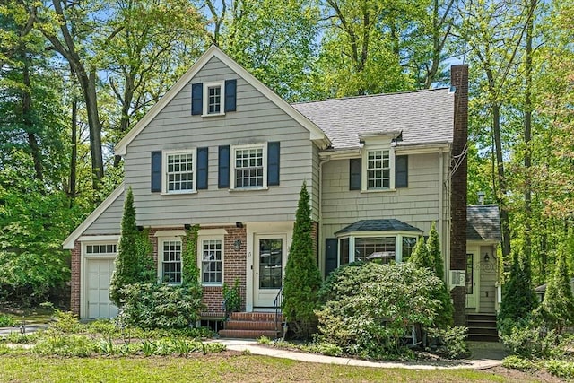 view of front of house with entry steps, a chimney, roof with shingles, brick siding, and an attached garage