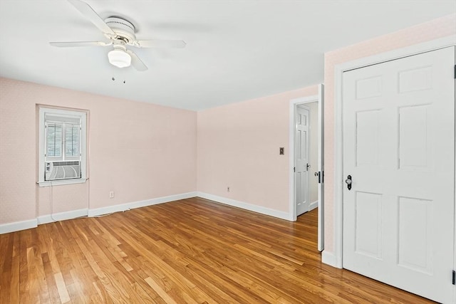 empty room featuring baseboards, light wood-style floors, ceiling fan, and cooling unit
