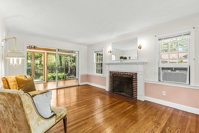 living area featuring plenty of natural light, cooling unit, wood finished floors, baseboards, and ornamental molding