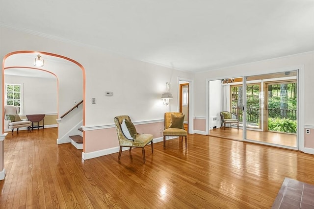 sitting room featuring wood finished floors, crown molding, stairs, and baseboards