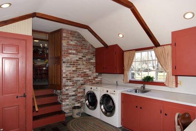 laundry area featuring brick wall, washer and clothes dryer, cabinets, and sink