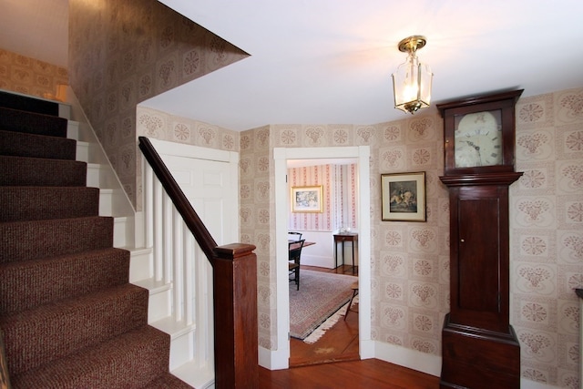 staircase with decorative columns and dark hardwood / wood-style flooring