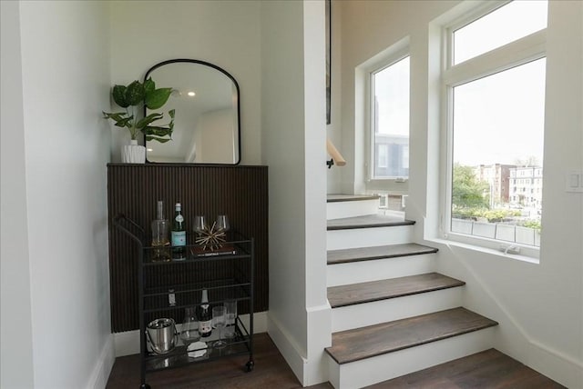 stairs with baseboards, wood finished floors, and a healthy amount of sunlight