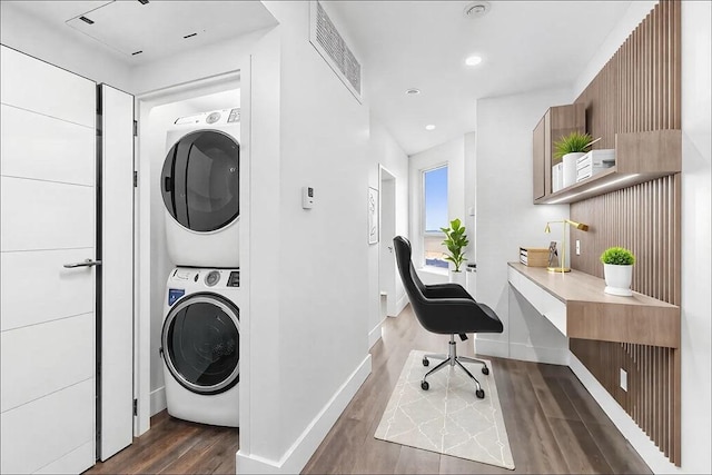 laundry room featuring baseboards, stacked washing maching and dryer, visible vents, laundry area, and wood finished floors