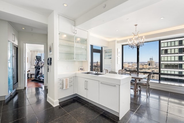 kitchen featuring sink, dark hardwood / wood-style flooring, a chandelier, decorative light fixtures, and white cabinetry