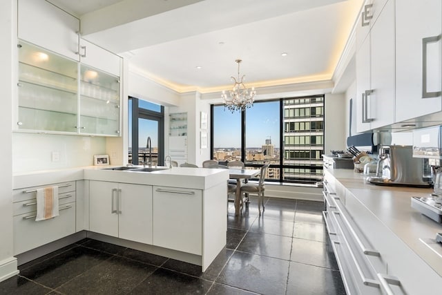 kitchen with an inviting chandelier, white cabinets, and dark tile flooring