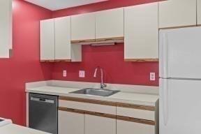 kitchen featuring light countertops, white cabinets, freestanding refrigerator, and dishwasher