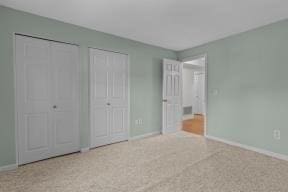 unfurnished bedroom featuring baseboards and two closets