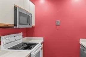 kitchen featuring light countertops, white range with electric cooktop, stainless steel microwave, and white cabinets