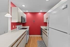 kitchen with recessed lighting, light countertops, light wood-style flooring, and white appliances