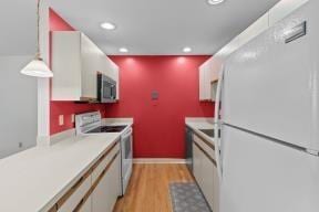 kitchen featuring light countertops, recessed lighting, white appliances, and light wood-style flooring