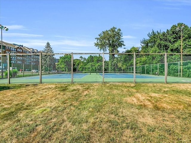 view of sport court featuring fence and a lawn