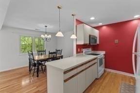 kitchen with freestanding refrigerator, light wood finished floors, stainless steel microwave, and white range with electric stovetop
