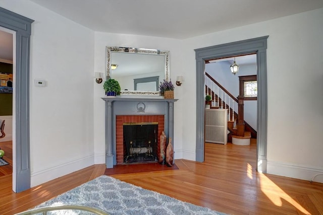 living room with a brick fireplace and wood-type flooring