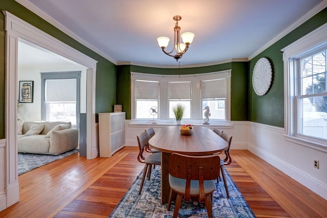 dining area with crown molding, a notable chandelier, and light wood-type flooring