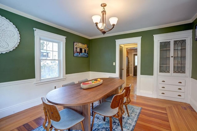 dining space with crown molding, light hardwood / wood-style floors, and a notable chandelier