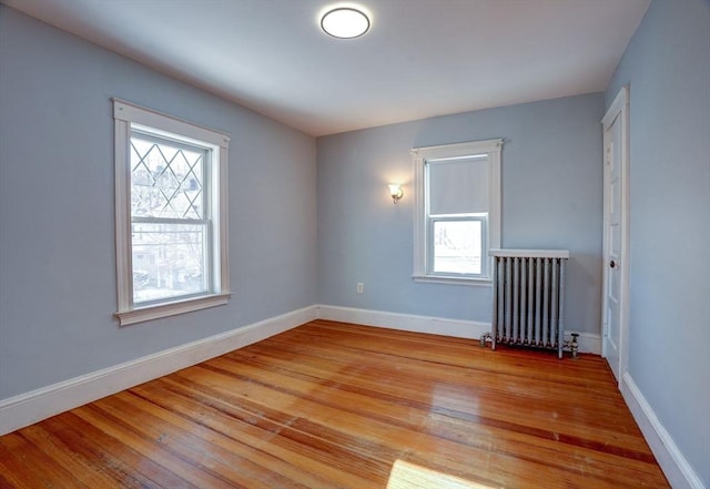 empty room featuring radiator heating unit, a healthy amount of sunlight, and light hardwood / wood-style floors