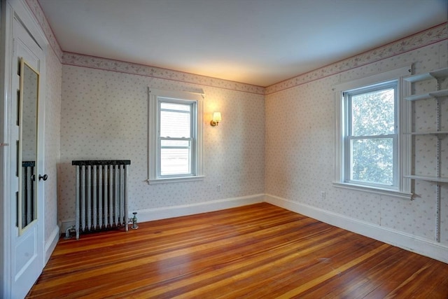 spare room with hardwood / wood-style flooring, radiator, and plenty of natural light