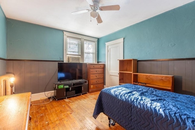 bedroom with radiator, ceiling fan, cooling unit, and light wood-type flooring