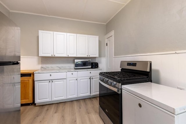 kitchen featuring backsplash, light hardwood / wood-style flooring, ornamental molding, appliances with stainless steel finishes, and white cabinetry