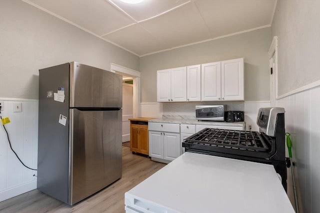 kitchen featuring light hardwood / wood-style flooring, decorative backsplash, ornamental molding, appliances with stainless steel finishes, and white cabinetry