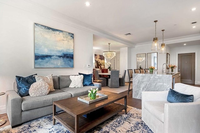 living room featuring visible vents, crown molding, baseboards, a notable chandelier, and light wood-style flooring