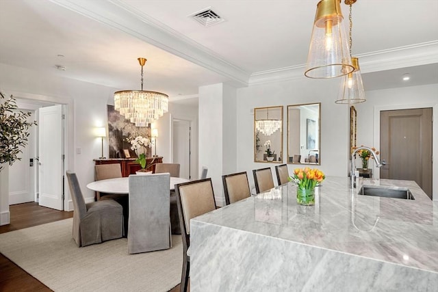 dining area with visible vents, wood finished floors, baseboards, an inviting chandelier, and ornamental molding