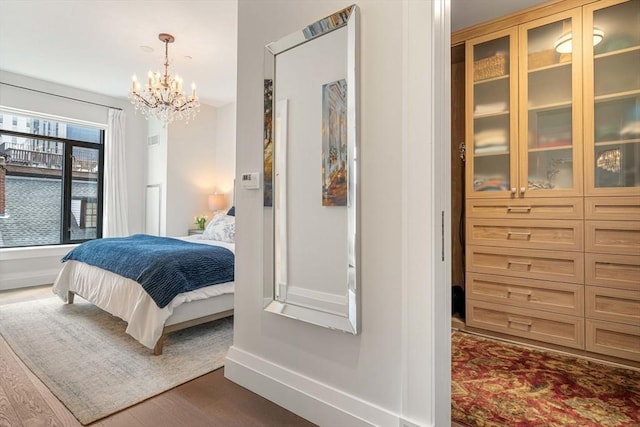 bedroom with an inviting chandelier, baseboards, and dark wood-style floors