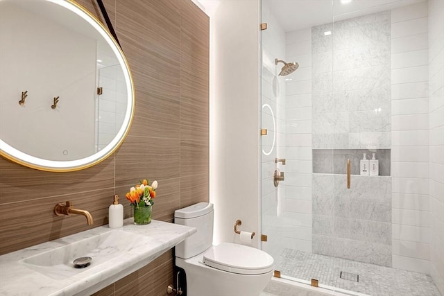 full bathroom with a sink, tile walls, toilet, and tiled shower