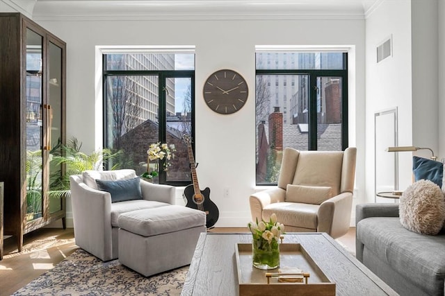interior space featuring visible vents, ornamental molding, wood finished floors, and a wealth of natural light