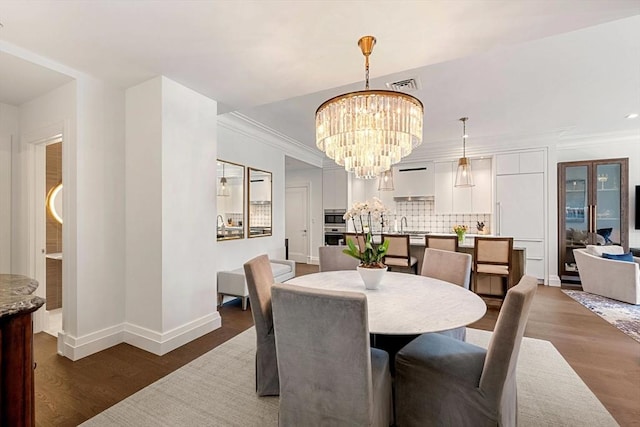 dining area featuring visible vents, wood finished floors, baseboards, a chandelier, and ornamental molding