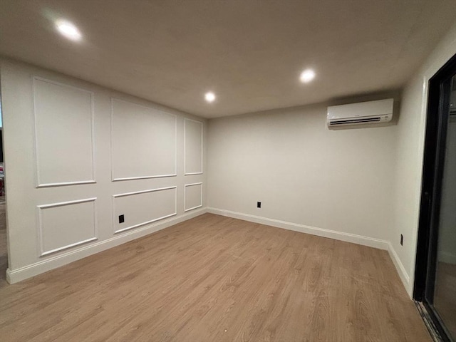 basement featuring an AC wall unit and light hardwood / wood-style flooring