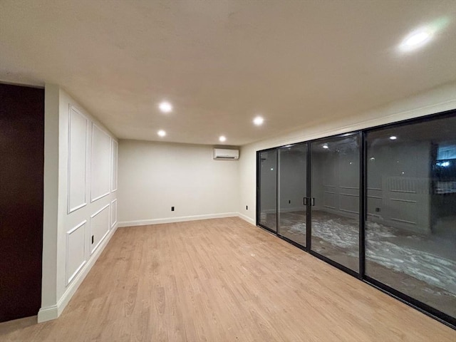 basement with light hardwood / wood-style flooring and a wall unit AC