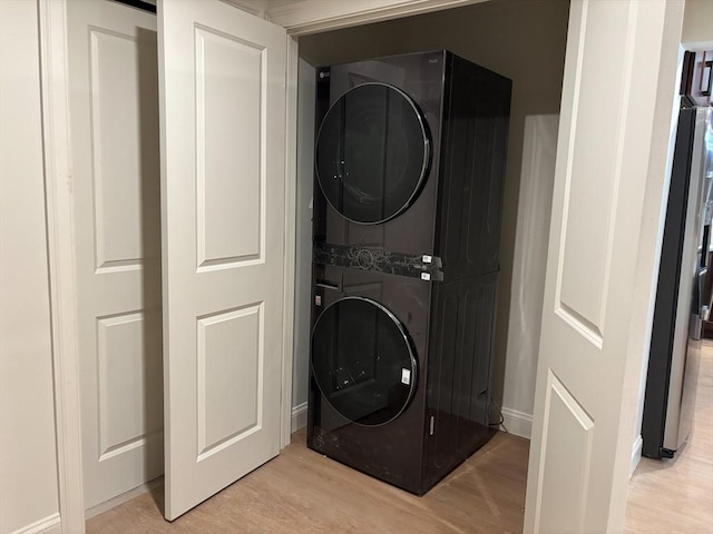 washroom with stacked washer / dryer and light hardwood / wood-style floors