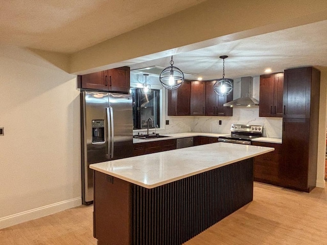 kitchen with hanging light fixtures, sink, a center island, wall chimney range hood, and stainless steel appliances