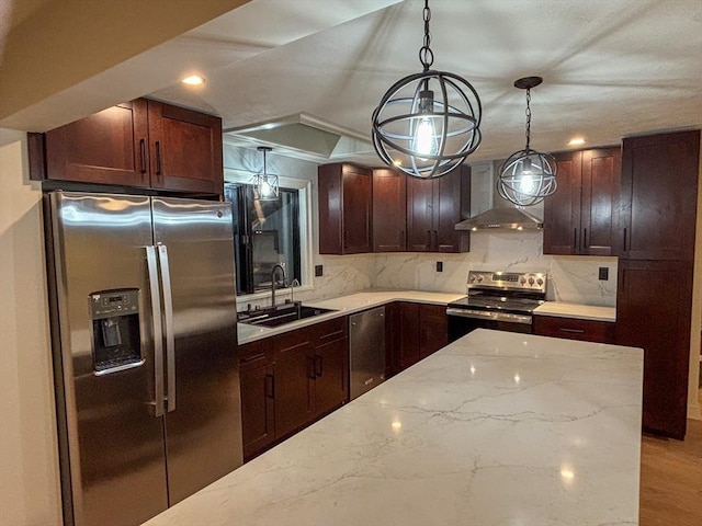 kitchen with light stone countertops, decorative light fixtures, wall chimney range hood, stainless steel appliances, and sink