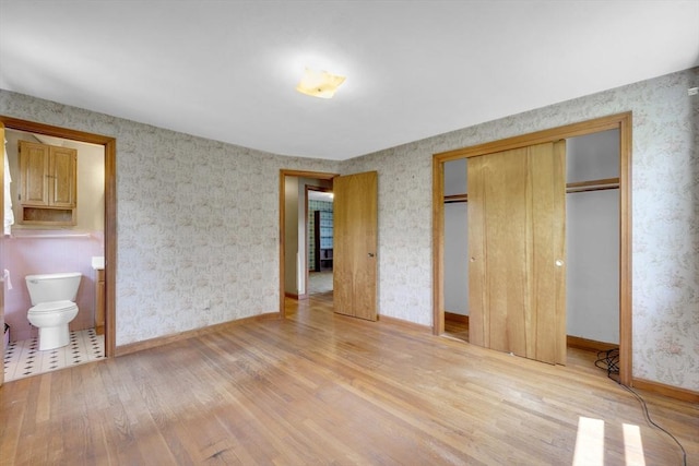 1032 Tinkham Rd, Wilbraham, MA 01095 - unfurnished bedroom featuring light wood-style flooring, wallpapered walls, a closet, baseboards, and connected bathroom