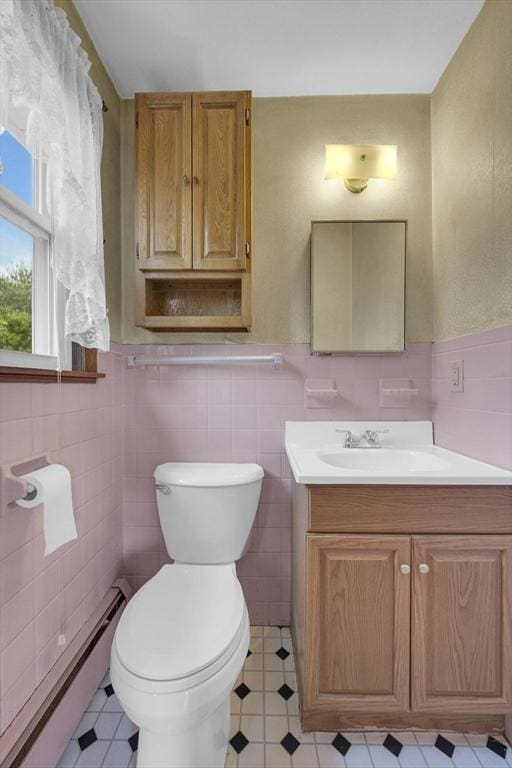 1032 Tinkham Rd, Wilbraham, MA 01095 - bathroom with a baseboard heating unit, vanity, toilet, tile walls, and a wainscoted wall