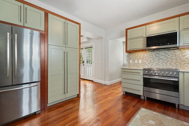 17 Perry St, Somerville, MA 02143 - kitchen featuring stainless steel appliances, dark wood-style flooring, green cabinets, tasteful backsplash, and light countertops
