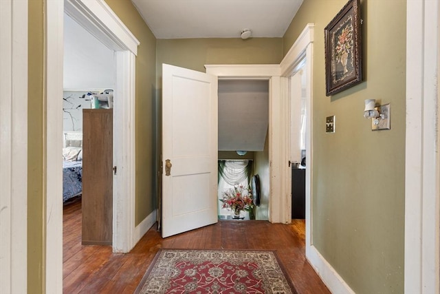 hallway with dark wood-style flooring and baseboards