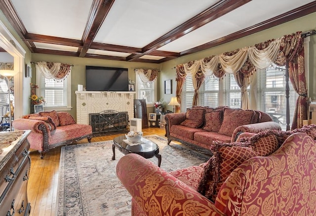 living room with coffered ceiling, ornamental molding, beamed ceiling, light wood-type flooring, and a brick fireplace