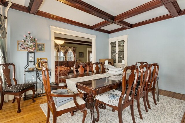 dining room with light wood-type flooring, beam ceiling, and coffered ceiling