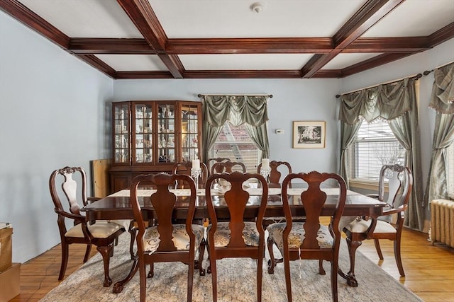 dining space featuring radiator, light wood finished floors, coffered ceiling, and beam ceiling