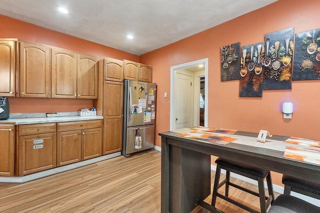 kitchen with recessed lighting, light countertops, light wood-style floors, freestanding refrigerator, and baseboards