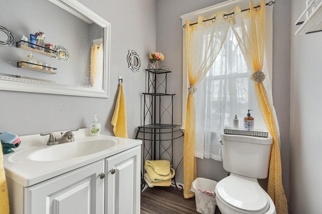 half bathroom with vanity, toilet, and wood finished floors