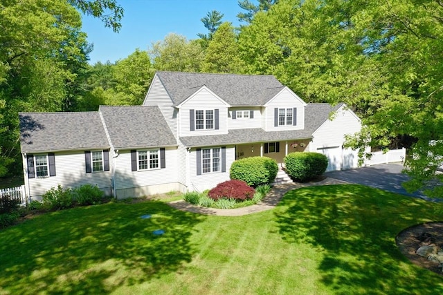 traditional-style home with asphalt driveway, a garage, and roof with shingles
