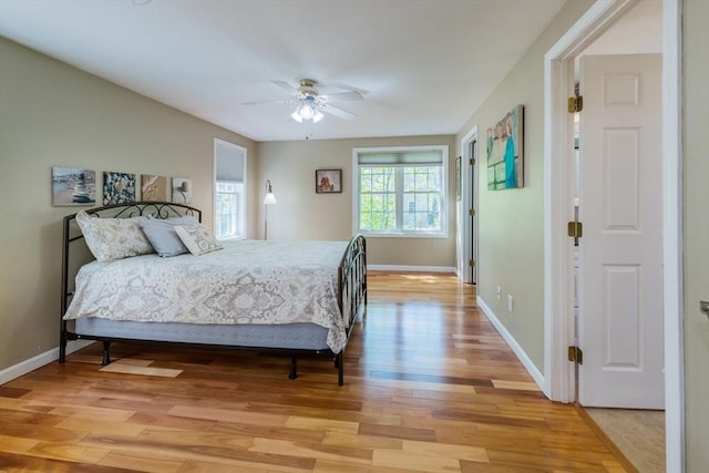 bedroom with light wood-style flooring, baseboards, and a ceiling fan
